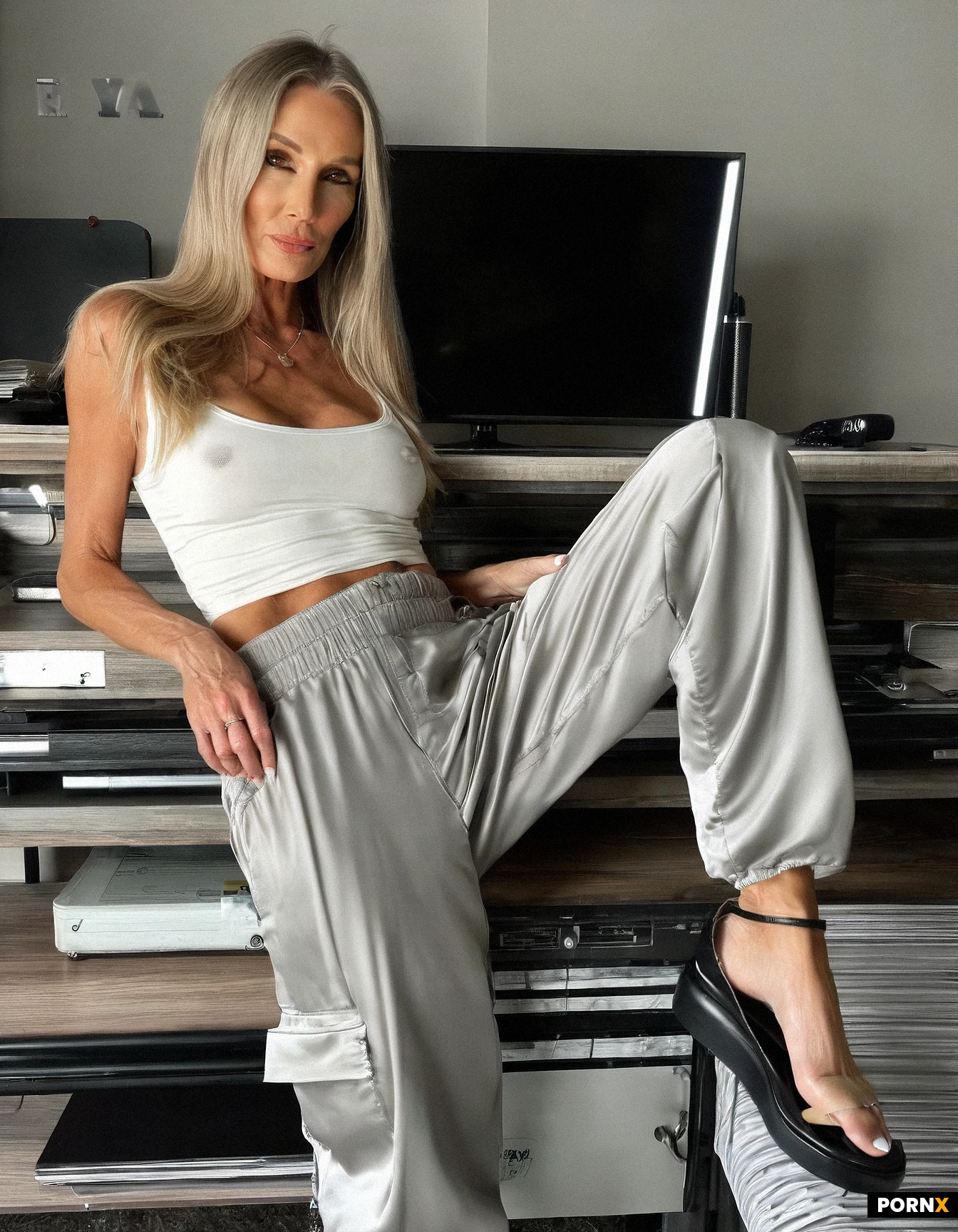 8k. hyper-detailed. Full body Side view ,52 years old long hair blonde woman medium build, brown eyes,(no bra,(nipple bulge):1.2,in a white thin silk skin tight tank top and loose fit grey cargo pants):1.7, in a small office standing legs spread apart, bright spot light from above.