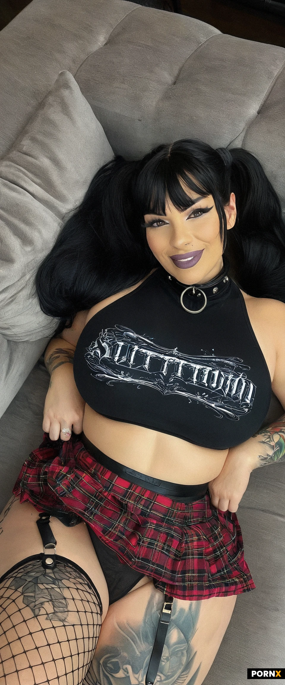 slutty milf, (mature woman), goth babe,((dark skin:1.4)),double high pigtails,busty lips,wide jaw,large eyes,goth makeup,fit body,thick thighs,huge breasts,slut collar,fishnet stockings,long black hair with colored highlights,pleated tartan mini skirt,Black tank top,bare stomach,stomach covered in tattoos,arms and hands covered in tattoos,lots of tattoos,large neck tattoos,seductive smile,on couch, LAYING on her back, panty pull,club,neon light,dark scene,intricate details,Photorealism,(Realistic:1.3),8k Resolution,(Clear image:1.3),