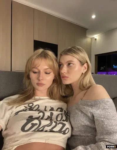 Two 19-year old women with blonde hair are on the couch watching TV